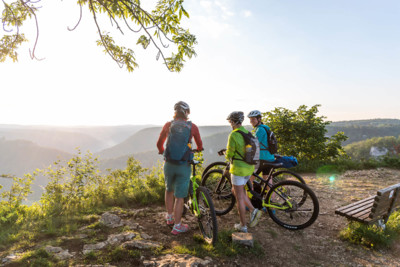 Drei Personen stehen mit ihren Fahrrädern an einem Aussichtspunkt und genießen die Aussicht über die Schwäbische Alb.